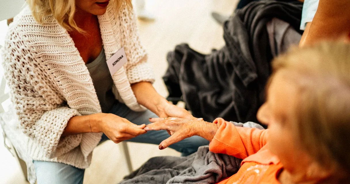 Cuidadora segurando as mãos de uma pessoa idosa em ambiente doméstico